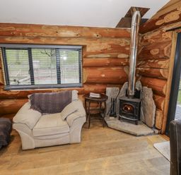 A living room with a wood stove and sofa at Douglas Cabin at Salford Court Farm Fishing Cabins near Clifton Upon Teme