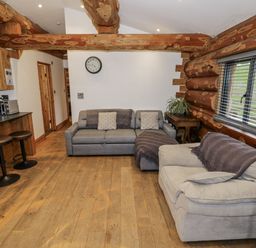 A living room with sofas and a kitchen counter at Douglas Cabin at Salford Court Farm Fishing Cabins near Clifton Upon Teme