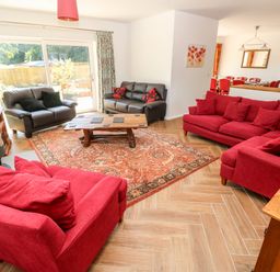 A living room with red and black sofas a wooden coffee table and patterned rug at 1 The Warren Robeston Wathen near Narberth