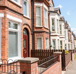 A row of terraced brick houses with fences along a sidewalk at Number 91 in Belfast County Antrim