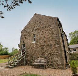 A stone cottage with steps leading to a door and a bench outside at 1 Roddam Rigg Cottage in Roddam near Wooler