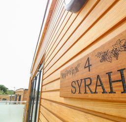 Exterior view of wooden buildings with balconies and a sign labeled syrah number 4 at Syrah in Seaview