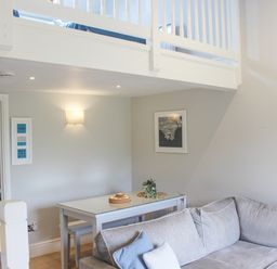 A dining table with benches next to a gray sofa in a living area at 5 Keeper's Cottage Hillfield Dartmouth