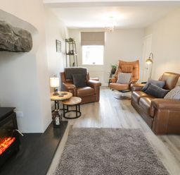 A living room with leather chairs a sofa a fireplace and a carpet at Minffordd in Trawsfynydd