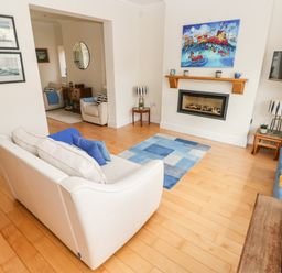 A living room with two sofas a fireplace and a colorful painting at The Headlands - Gower in The Mumbles