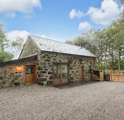 A stone house with wooden doors and a gravel driveway at Yr Hen Oriel in Llanrug