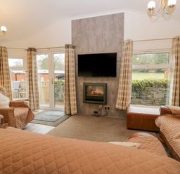 A living room with couches armchair wall-mounted TV and fireplace at Wansfell View Limefitt Park near Troutbeck