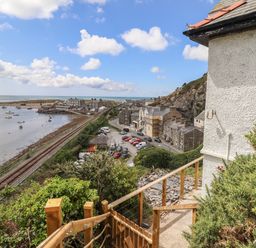 A coastal view with a railway track and houses near the shore at Windycroft in Barmouth