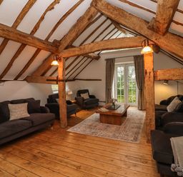 A living room with wooden beams dark sofas coffee table and rug at 1 White House Cottages Bromsash near Lea