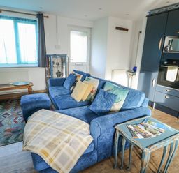 A living room with a blue sofa and coffee table at 7 Bro Branwen Aberffraw near Rhosneigr