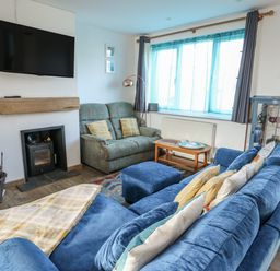 A living room with a television and sofa at 7 Bro Branwen Aberffraw near Rhosneigr
