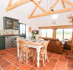 A kitchen and dining area with wooden beams and tiled floor at Little Barn in Tittleshall