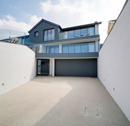 A driveway leading to a modern house with large windows and a garage at Megizzy in Polzeath
