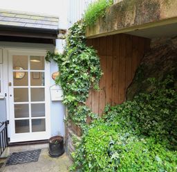 A white door with glass panels next to a plant-covered wooden wall outside a building at Ferry View in Dartmouth