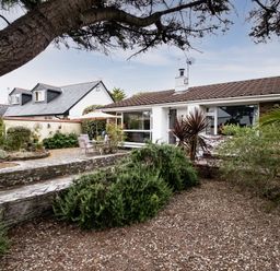 A garden with shrubs and patio furniture outside a bungalow at Longhouse Bungalow in Rock