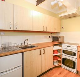 A kitchen with wooden cabinets a white stove a microwave a sink and a small refrigerator at 16 Norfolk Heights Docking