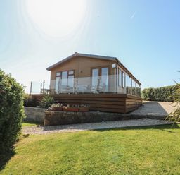 A lodge with glass railing and plants at Sunstone Lodge (Garreg Haul Lodge) Cilan near Abersoch