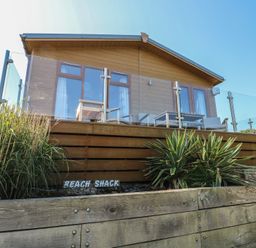 A lodge with a balcony and a wooden deck at Sunstone Lodge (Garreg Haul Lodge) Cilan near Abersoch