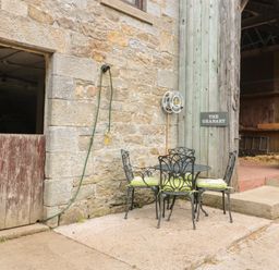 Metal table and chairs with cushions outside a stone and wooden building with a sign saying The Granary in Rothbury