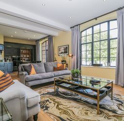 A living room with gray sofas orange striped pillows a glass coffee table and large window at Tarn End Cottages 5 Talkin near Brampton Cumbria