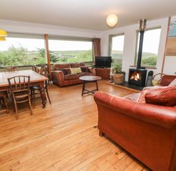 A living room with brown leather sofas a wooden dining table and chairs a fireplace and a television at Porth Farm Annexe Mawgan Porth