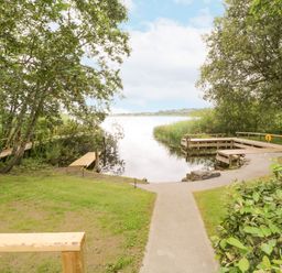 A lakefront area with wooden docks and a pathway surrounded by trees at Port Heron Lodge in Ballykeeran near Glasson County Westmeath