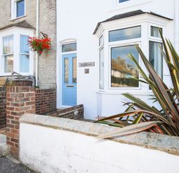 The exterior of a house with a blue door a bay window brick walls and plants outside at The Shambles in Fortuneswell