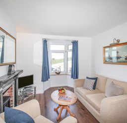 A living room with beige sofas a wooden coffee table a television and a painting at The Shambles in Fortuneswell
