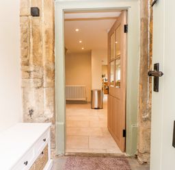 An open wooden door showing a hallway with a radiator and a trash bin at 4 Lower Folley in Chipping Campden