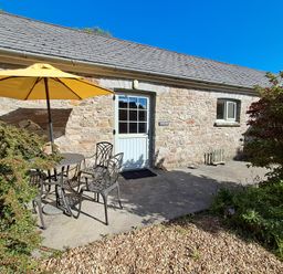 An outdoor area with a table and chairs under an umbrella at Carreg Cennen Cottage Llandeilo