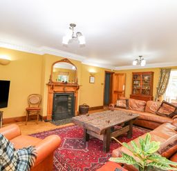 A living room with leather sofas wooden coffee table fireplace and television at The Firs in Wendling near Dereham