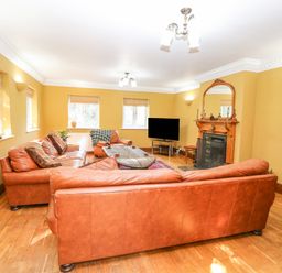 A living room with leather sofas a fireplace television and windows at The Firs in Wendling near Dereham