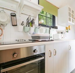 A kitchen counter with a built in oven stovetop utensils kettle toaster and a sink at High Rigg Shepherd's Sunset in Brampton Cumbria