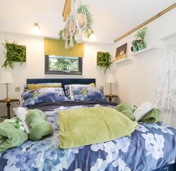 A bedroom with a bed covered in floral bedding and green towels at High Rigg Shepherd's Sunset in Brampton Cumbria