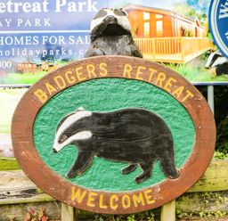 A wooden sign with a badger image and text reading Badgers Retreat Welcome at Badgers Retreat Tunstall near Hipswell