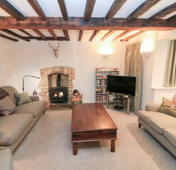 A living room with a fireplace and television at Butlers Cottage in Burford