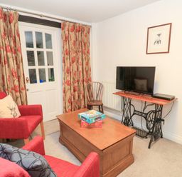 A living room with a coffee table and a television at Butlers Cottage in Burford