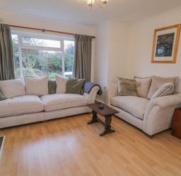 A living room with beige sofas and green curtains and a small wooden table at Sea Change in Newholm near Whitby