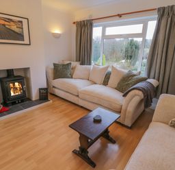 A living room with a wood burning stove two beige sofas and a wooden coffee table at Sea Change in Newholm near Whitby