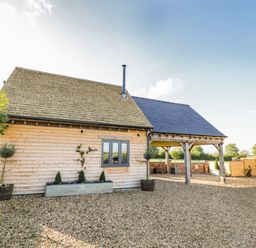 A wooden house with a gravel driveway and potted plants at The Hyde in Armscote near Newbold on Stour