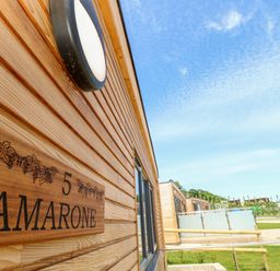 The exterior of a wooden building with a sign reading Amarone number 5 and a circular light above at Amarone in Seaview