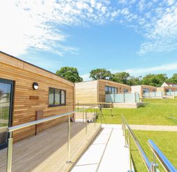 A row of wooden lodges with glass railings and grassy surroundings at Amarone in Seaview