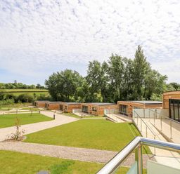 A row of wooden cabins with glass doors and metal railings on a grassy landscape at Amarone in Seaview