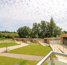 A row of wooden cabins with patios and walkways surrounded by grass and trees at Champagne in Seaview