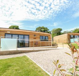 Two modern wooden cabins with glass doors and railings surrounded by grass and gravel at Cava in Seaview