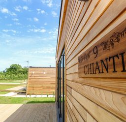 The exterior of a wooden cabin with a sign reading Chianti and a view of another wooden cabin in a grassy area at Chianti in Seaview