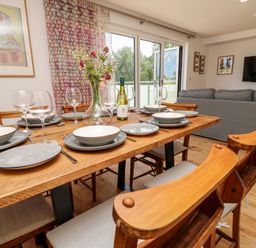 A dining area with a wooden table set with plates glasses and cutlery in an open plan living room at Claret in Seaview