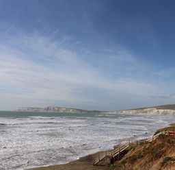 A coastline with waves hitting the shore and white cliffs in the distance at Muscat Seaview