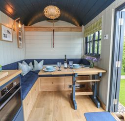 A compact dining area with a wooden table set with plates and glasses in a small cabin at Merlot in Pondwell near Seaview