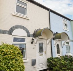 A row of brick houses with white and blue painted exteriors with plants in front at Little Tern in Brewers Quay Harbour